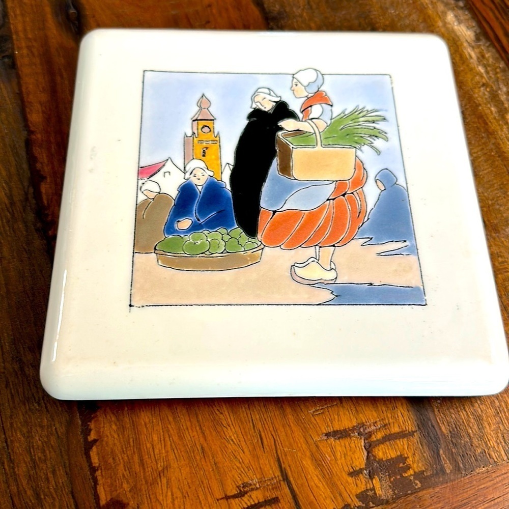 Handpainted glazed trivet 6.25“ X 6.25” depicting market scene made in Belgium